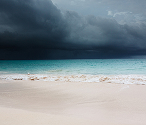A dark and stormy sky over an ocean front beach.