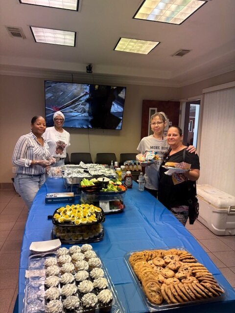 Women standing around a table of food.